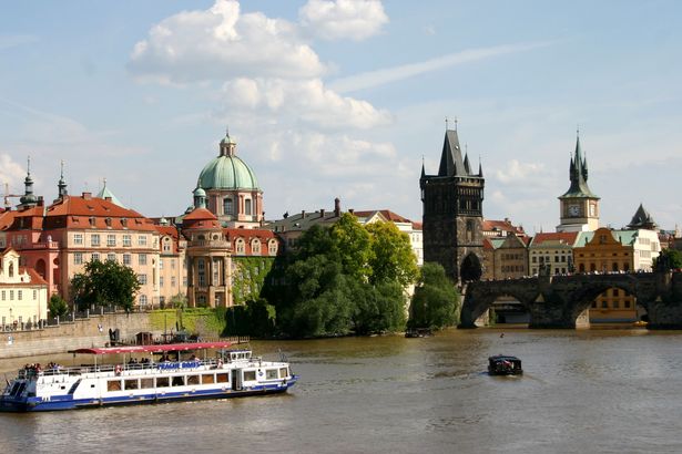 Blick auf die Prager Burg und die Karlsbrücke bei Sonnenuntergang, von der Moldau aus gesehen.