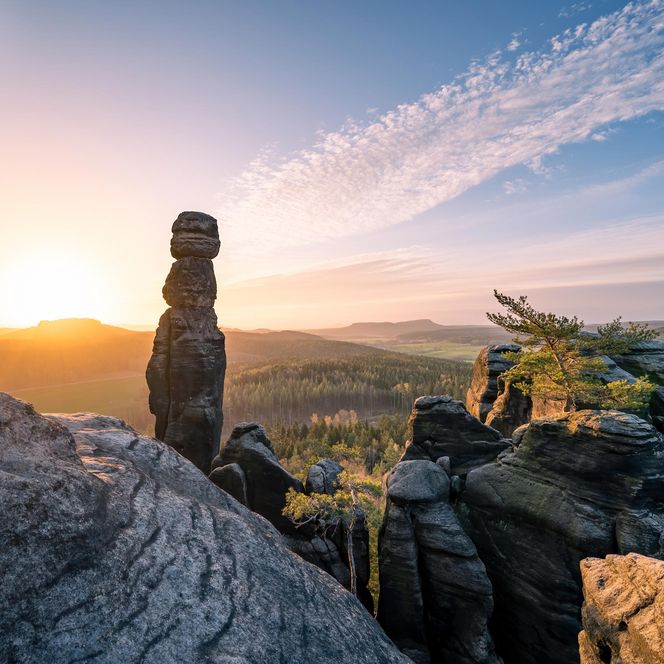 Sonnenaufgang über einer felsigen Landschaft mit einer markanten Steinformation, der Barbarine im Vordergrund.