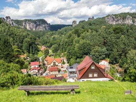 Blick auf ein malerisches Dorf mit bunten Häusern, umgeben von grünen Wäldern und Felsen.