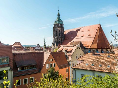 Historische Kirche in Pirna, von Gebäuden umgeben, blauer Himmel im Hintergrund.