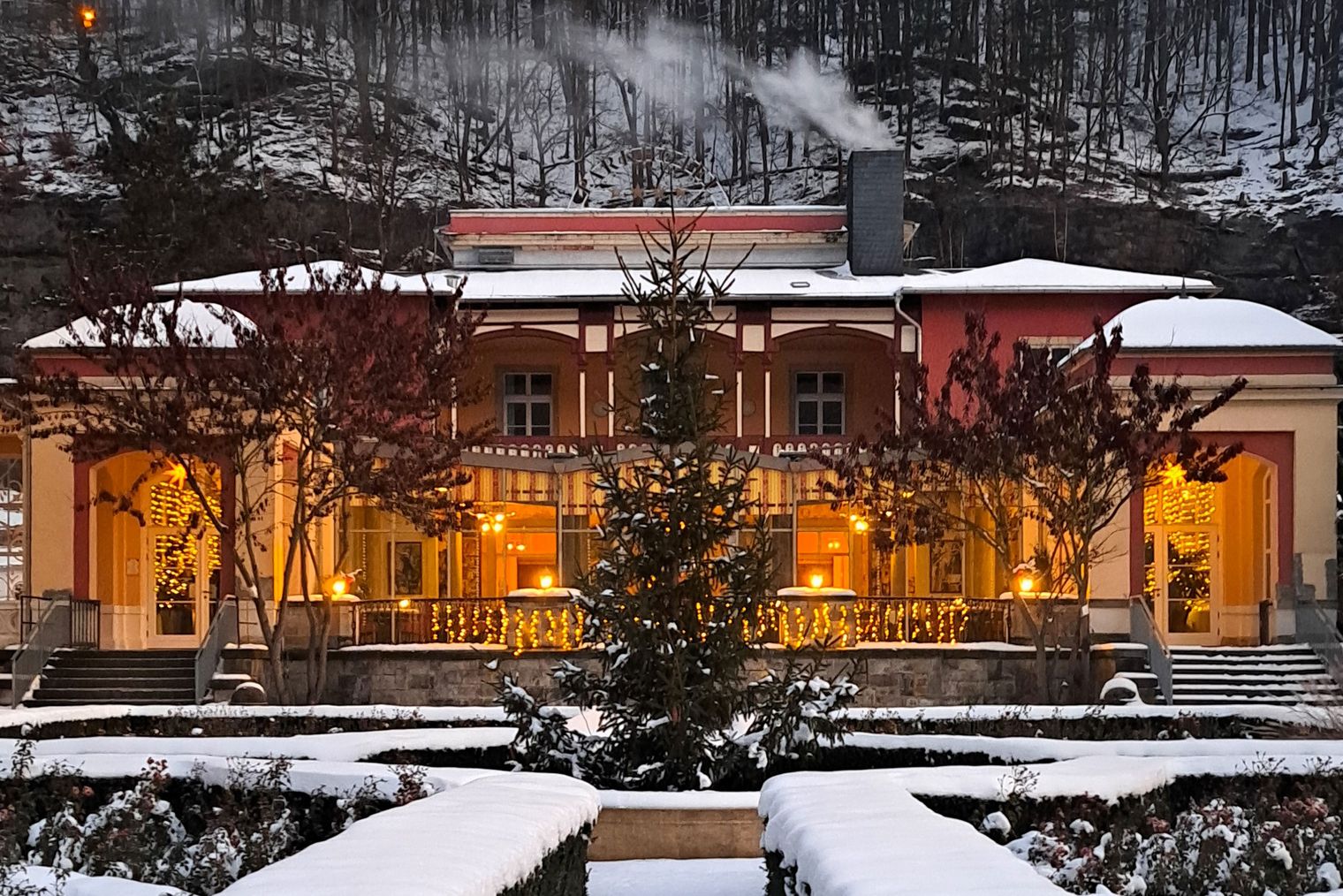 Weihnachtlich dekoriertes Gebäude mit Lichtern und Schnee im Hintergrund.