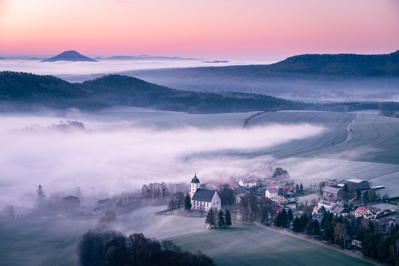 Fachwerkhaus mit rotem Satteldach, umgeben von grünen Pflanzen und blauem Himmel.