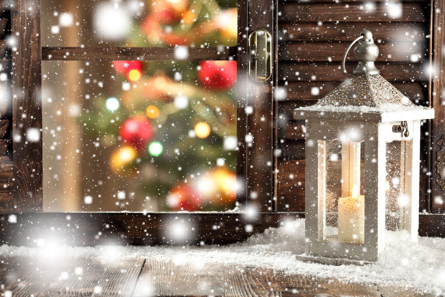 Adventstimmung mit Laterne vor einem Fenster, Schnee, Weihnachtsbaum hinter Fenster, Kerze in Laterne