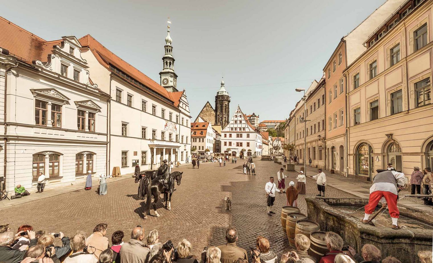 Blick auf eine belebte Straße mit historischen Gebäuden und Menschen, die sich versammeln.