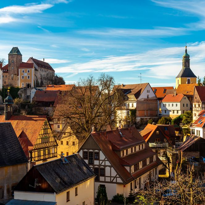 Blick auf das malerische Hohnstein mit historischen Gebäuden, einer Kirche und bunten Herbstbäumen.