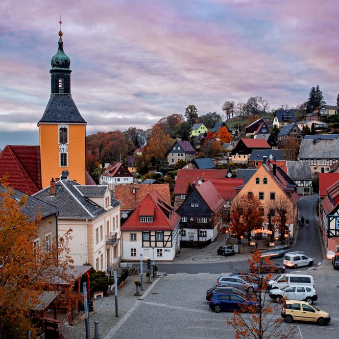 Blick auf eine malerische Stadt mit bunten Häusern und einem Kirchturm bei Sonnenuntergang.
