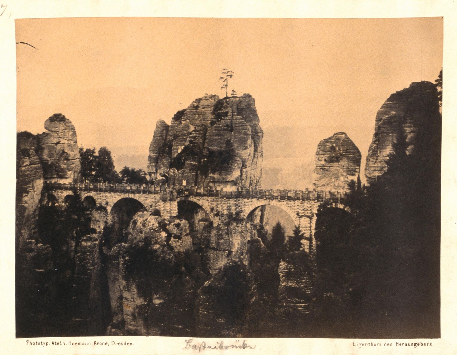 Historische Schwarz-Weiß-Fotografie der Basteibrücke zwischen Felsen und Bergen.