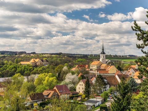 Panorama von Dohna mit grünen Hügeln, blauer Himmel und einer Kirche im Vordergrund.