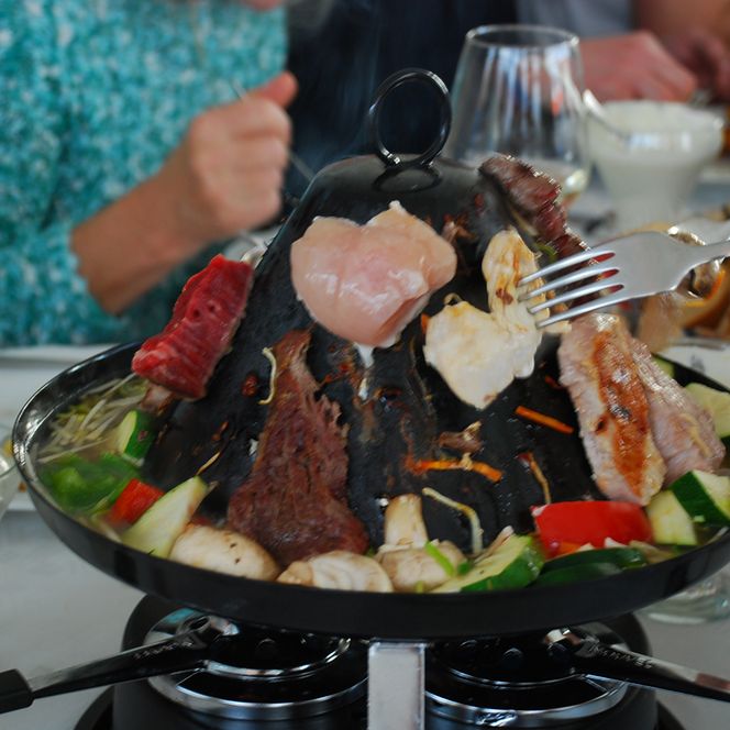 Ein Tisch mit einem großen Topf voller Fleisch und Gemüse, dampfend und appetitlich angerichtet.