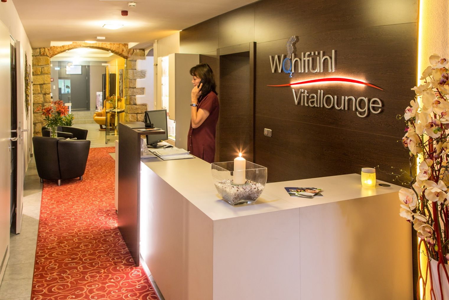 Wellnessbereich mit Steinwänden, einer Sitzbank und einem Zugang zu einem weiteren Raum.
