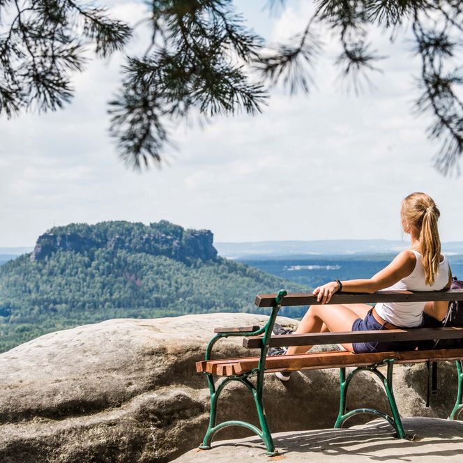 Frau sitzt auf einer Bank und blickt auf den Lilienstein.