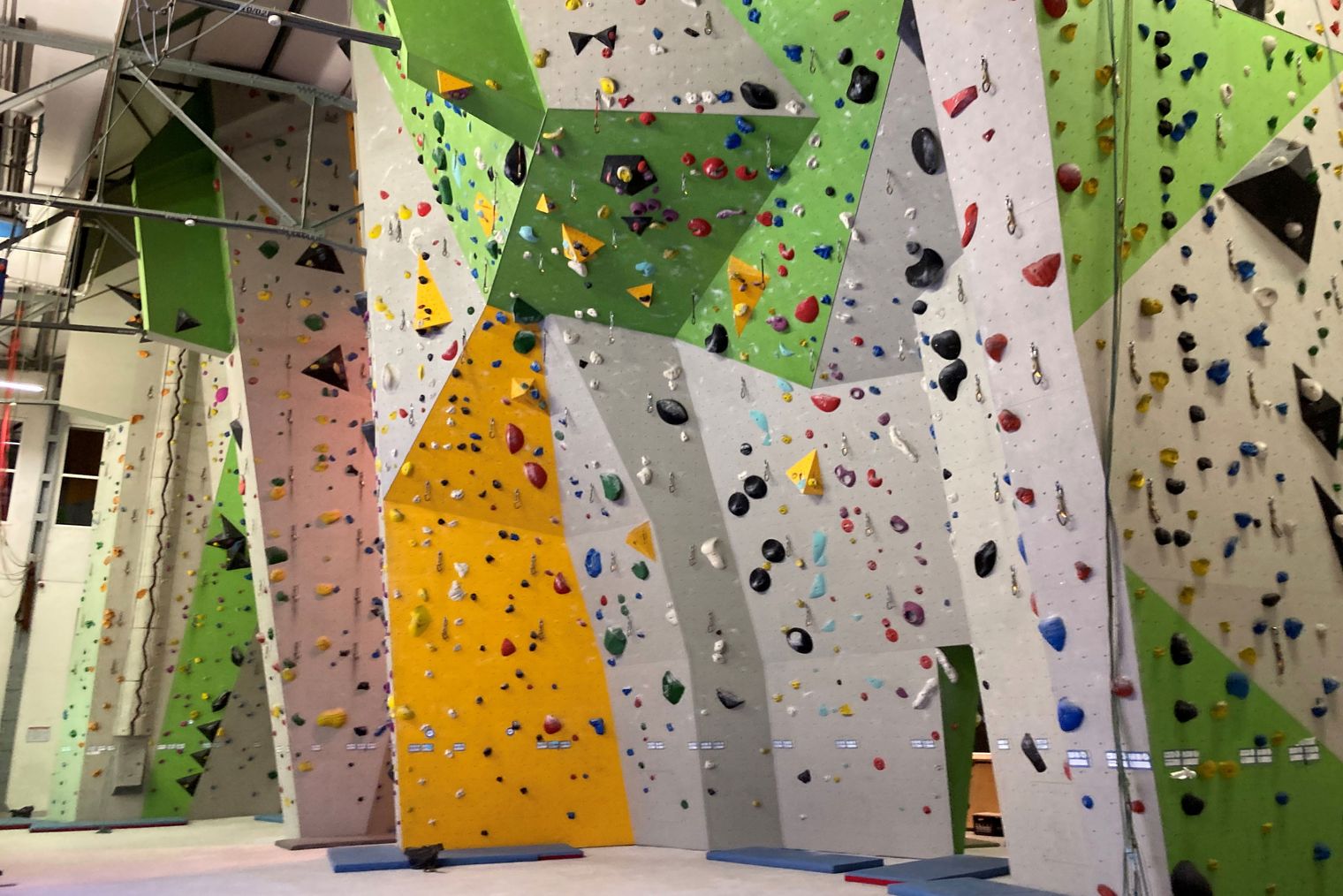 Bunte Kletterwand mit Griffen in einer Indoor-Kletterhalle.