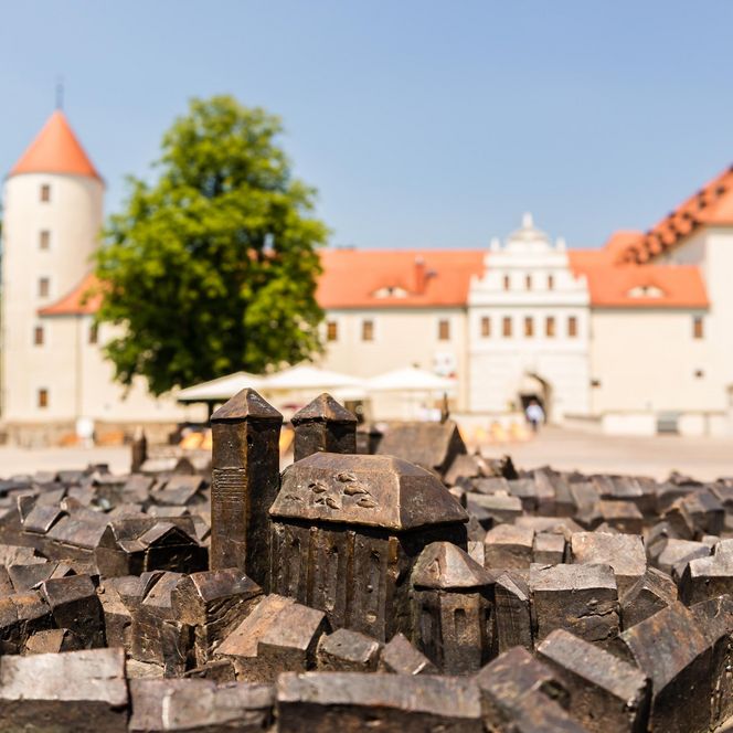 Modell einer Stadt aus Holz mit einem Schloss im Hintergrund und blauem Himmel.