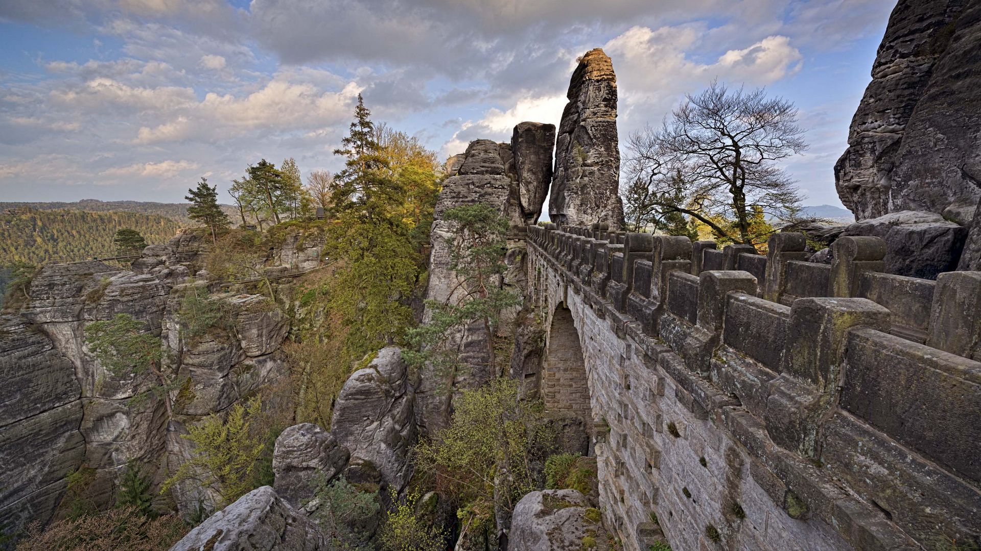 Steinerne Brücke über Schlucht im Gebirge, bewaldet.
