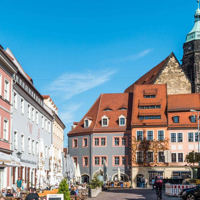 Bunte Gebäude und ein Kirchturm unter blauem Himmel in einer Stadtansicht.