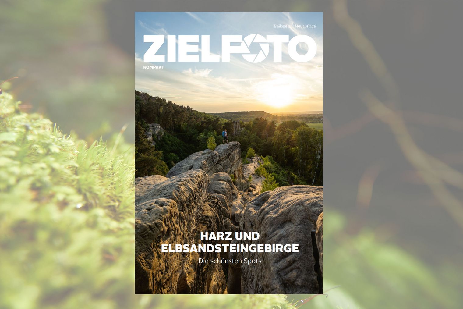 Titelseite Zielfoto Magazin Ausgabe 2 Titelseite eines Magazins mit einem Foto auf welchem ein Wanderer auf einem Felsvorsprung steht, grüner Landschaft im Hintergrund und Sonnenuntergang.