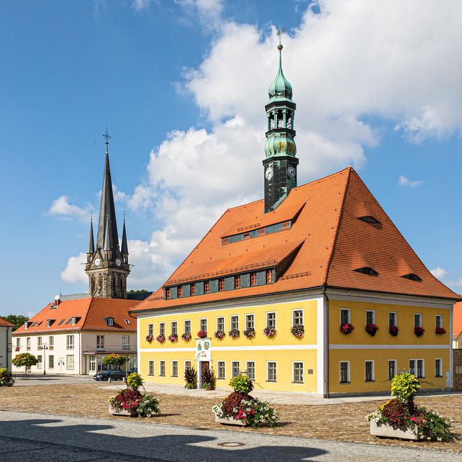 Farbige Gebäude mit roten Dächern und Türmen unter blauem Himmel mit Wolken.