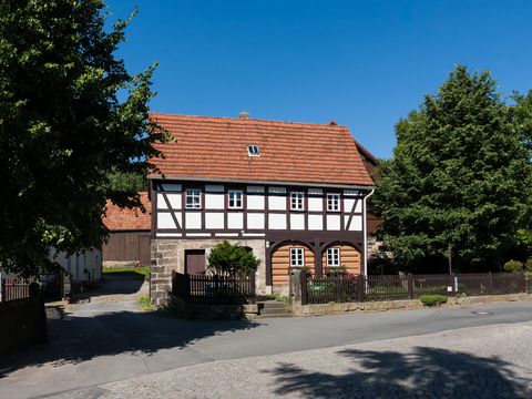 Heimatstube Reinhardtsdorf-Schöna: Fachwerkhaus mit rotem Dach, grüner Umgebung, blauer Himmel.