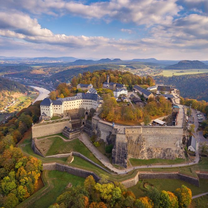 Luftaufnahme einer Burg auf einem Hügel, umgeben von Bäumen und Landschaft.