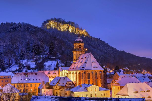 Blaue Stunde über der Festung Königstein, beleuchtet, vor blauem Himmel.