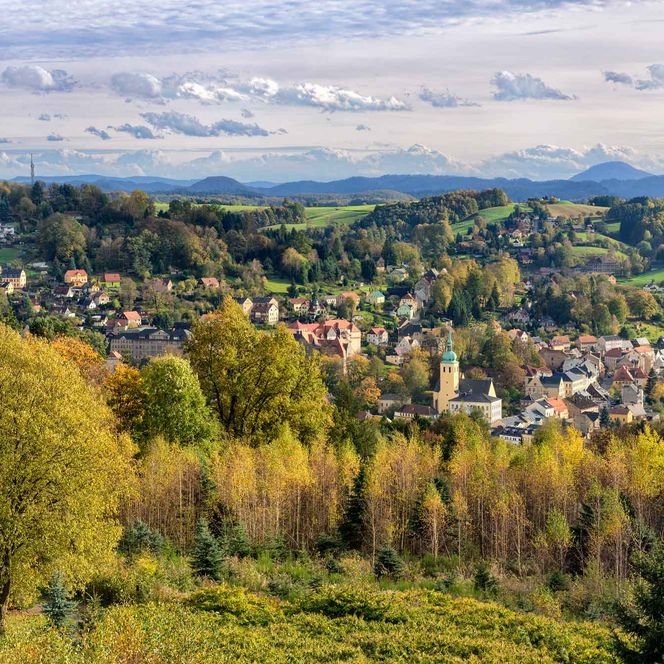 Blick auf eine malerische Landschaft mit bunten Bäumen und einem kleinen Ort im Tal.