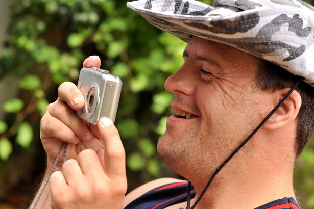 ein fröhlicher Mensch mit Down-Syndrom fotografiert