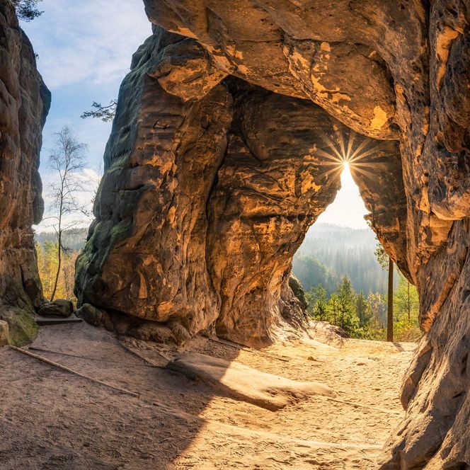 Sonnenstrahlen scheinen durch eine Felsöffnung der Kleinsteinhöhle.