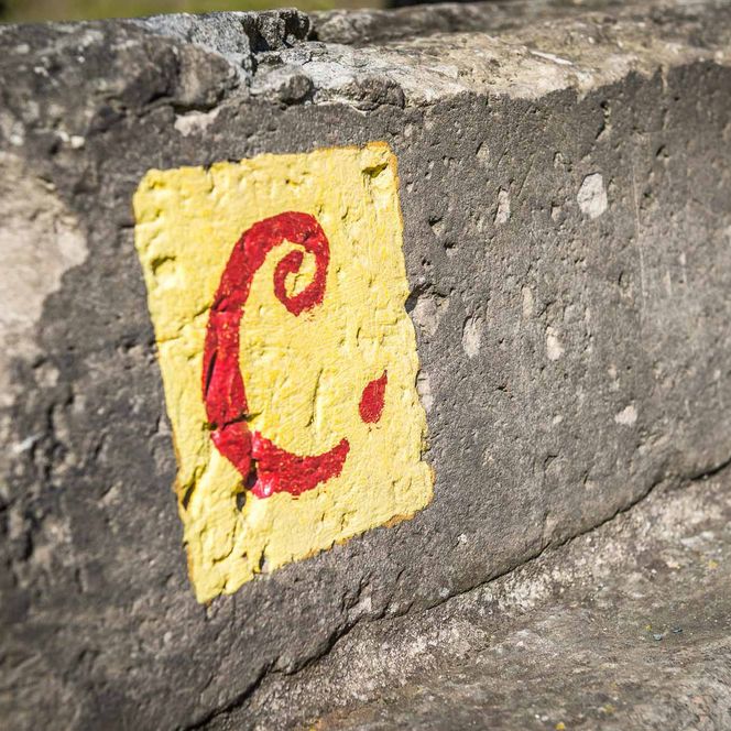 Gelbe Markierung mit rotem "C" auf einem grauen Betonblock.