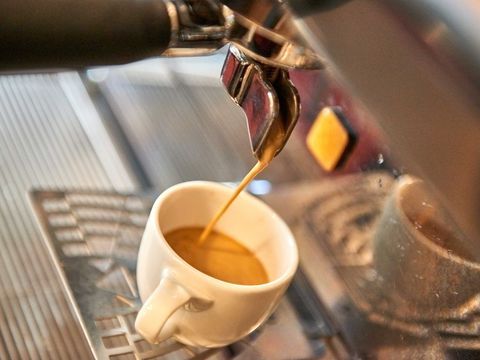 Kaffeemaschine die Kaffee in weiße Tasse einlaufen lässt.