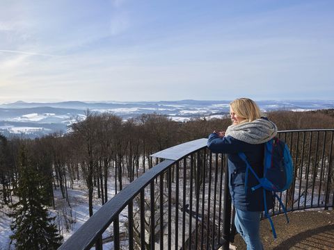 Aussichtsturm auf einem bewaldeten Hügel, Blick auf die verschneite Landschaft.