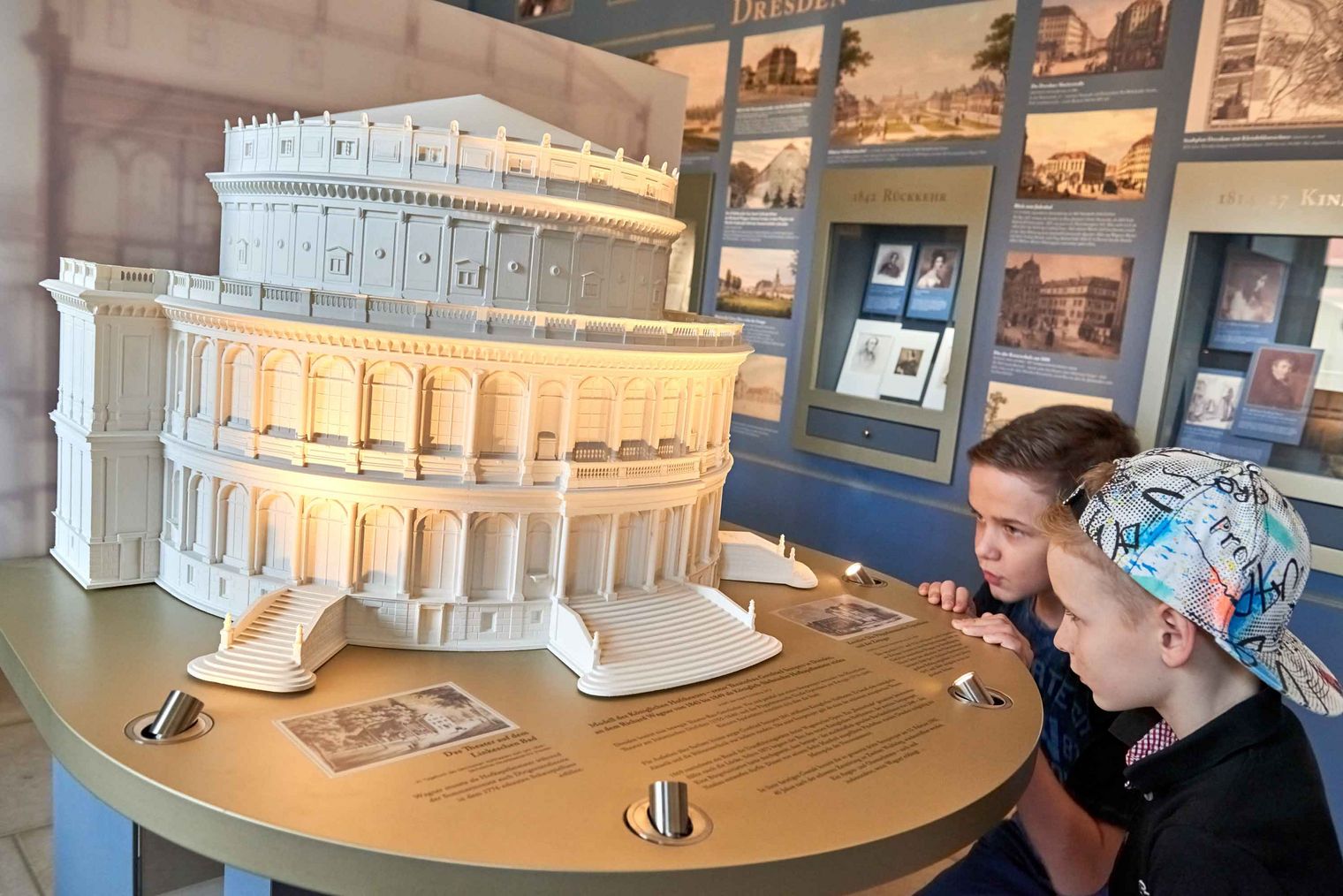 Zwei Kinder betrachten ein Modell der Semperoper Dresden, welches auf einem Tisch steht.