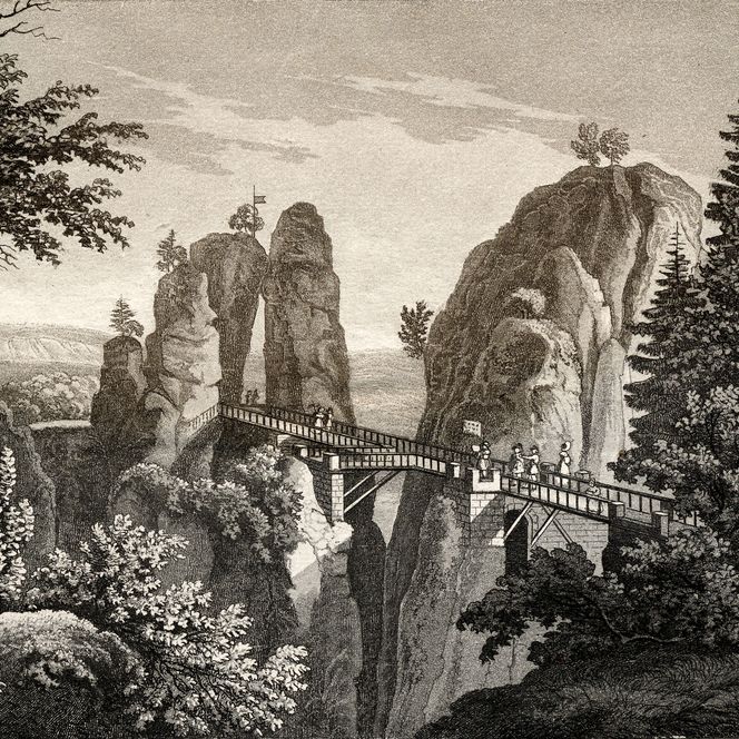 Felsformationen mit einer Brücke, umgeben von Bäumen und einer Landschaft im Hintergrund.
