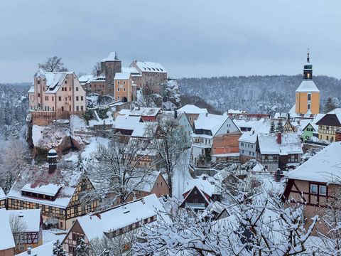 Burg Hohnstein auf schneebedecktenHügel im Sonnenlicht, heller Himmel.