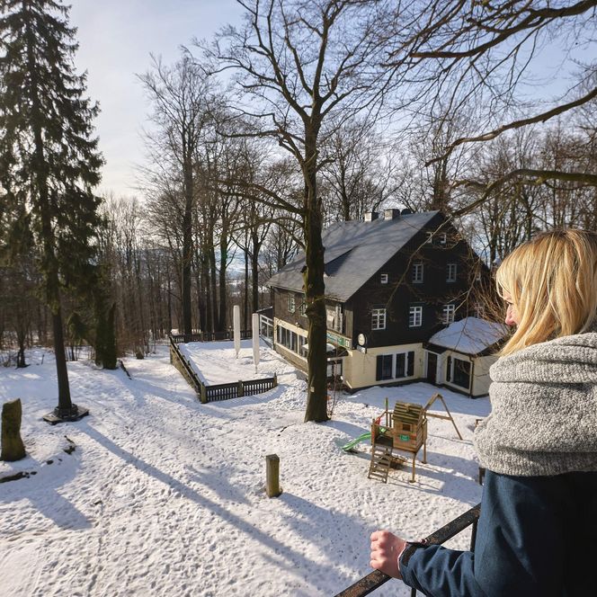 Person mit blonden Haaren in warmer Kleidung steht in einer verschneiten Landschaft vor der Einkehr am Ungerberg.