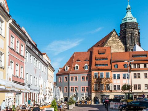 Historischer Marktplatz in Pirna mit bunten Gebäuden und Menschen bei sonnigem Wetter.