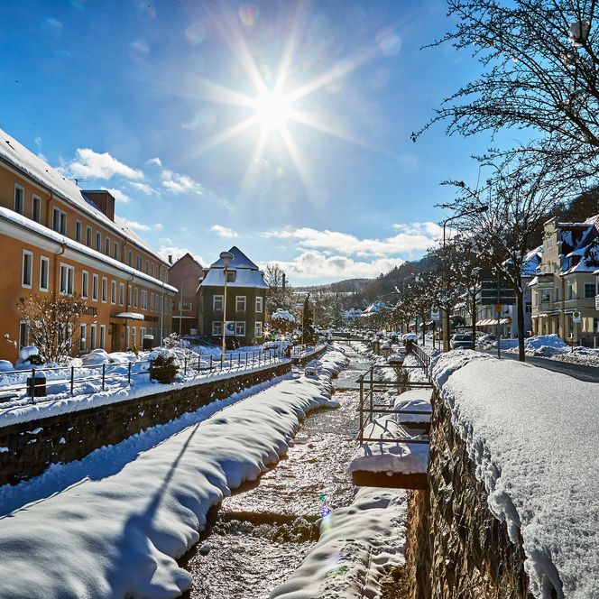 Sonniger Wintertag mit schneebedeckten Gebäuden und einem klaren blauen Himmel.