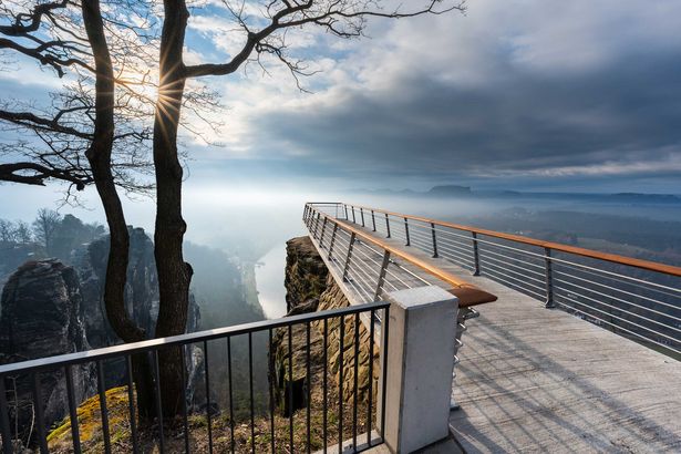 Neue Basteiaussicht: Steinerne Aussichtsplattform über einer Schlucht, bewölkter Himmel im Hintergrund.