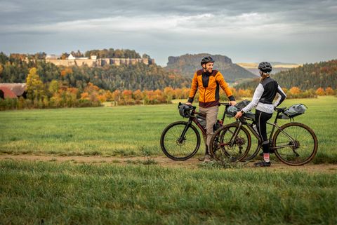Zwei RockHead-Gravelbiker stehen bei Leupoldishain auf einem Weg und schauen in Richtung Festung Königstein und Lilienstein