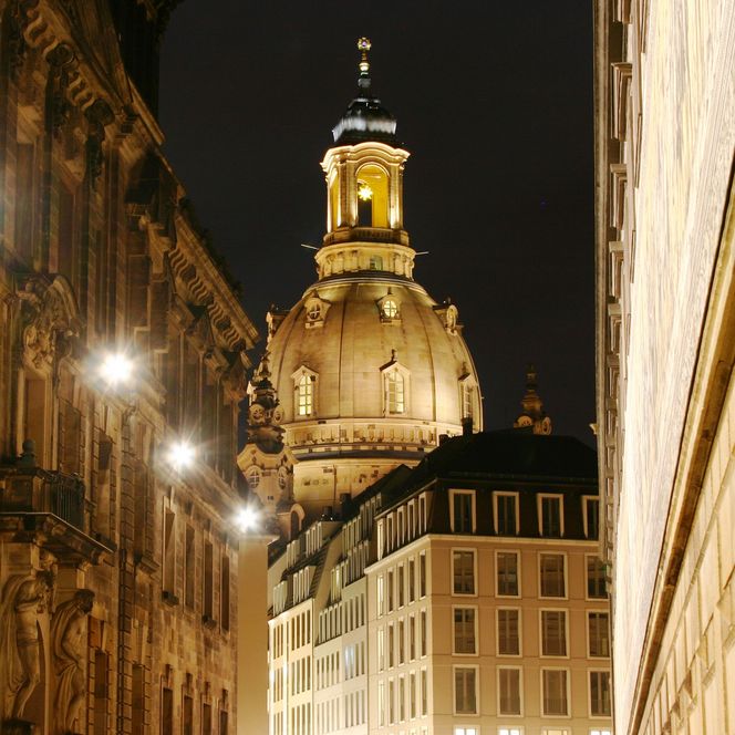 Beleuchtete Straßen mit einem Blick auf eine Kuppel im Hintergrund bei Nacht.