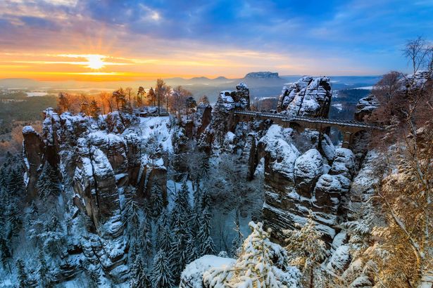 Verschneite Bastei-Brücke in sächsischer Felsenlandschaft bei klarem Winterwetter.