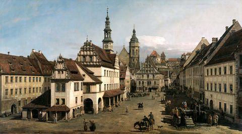 Historische Stadtansicht von Pirna mit Gebäuden, Türmen und einer belebten Straße.
