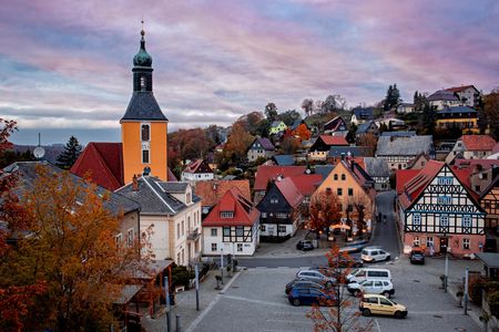 Blick auf eine malerische Stadt mit bunten Häusern und einem Kirchturm bei Sonnenuntergang.