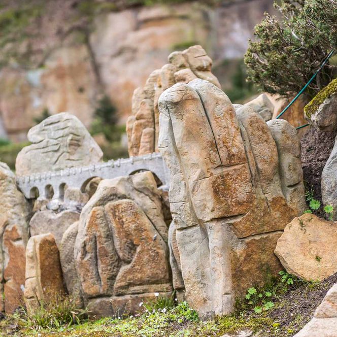 Verschiedene Steinskulpturen und -reliefs in einer natürlichen Umgebung.