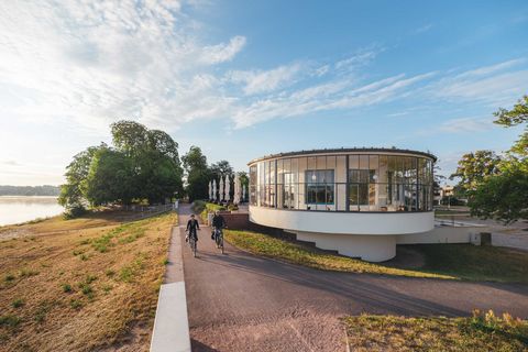 Radfahrer fahren an moderner runden Architektur des Kornhaus Dessau am Flussufer der Elbe vorbei.