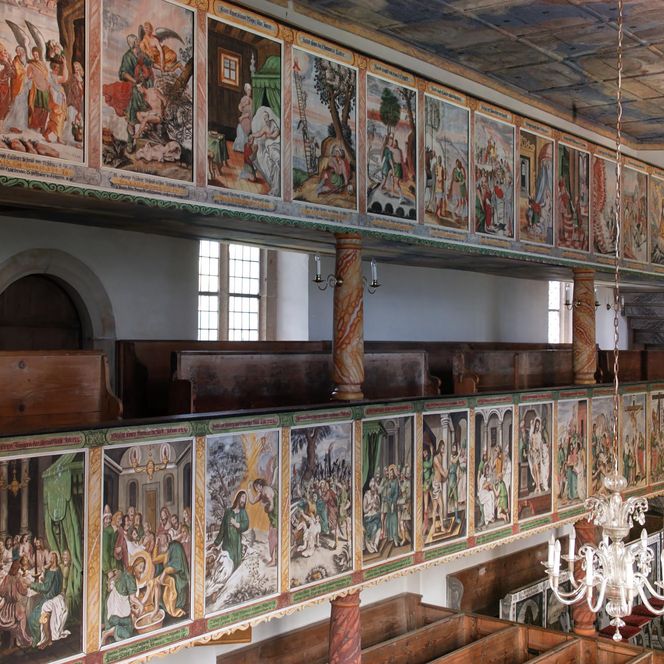 Blick auf eine Kirche mit bunten Wandmalereien und Holzbalustraden.