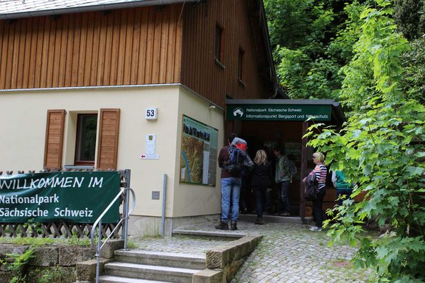Nationalparkinfostelle in Schmilka: Historisches Gebäude mit Holzverkleidung und dunklem Dach im Park.