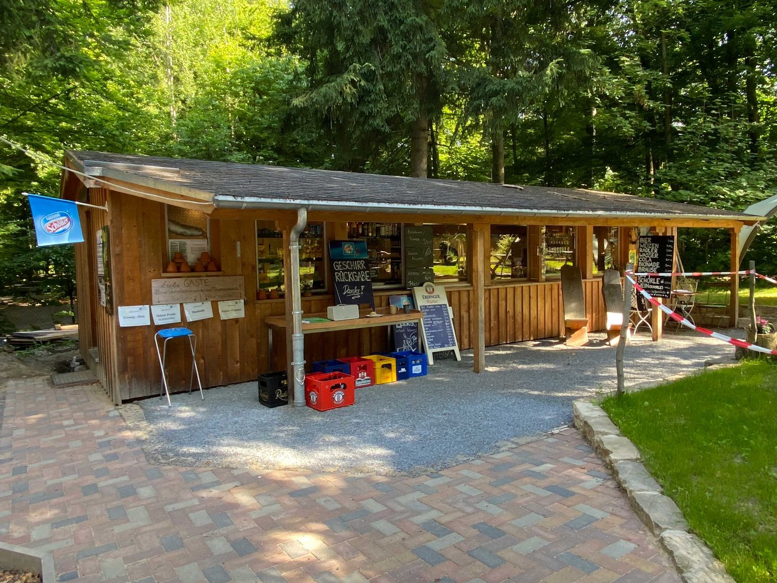 Holzhütte der Bergwirtschaft Steinerner Tisch im Wald mit Fenstern, Tischen und bunten Spielzeugen im Außenbereich.