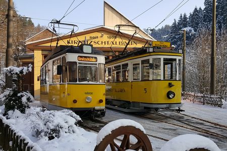 Zwei gelbe Straßenbahnen stehen unter einem überdachten Bahnsteig im Schnee.