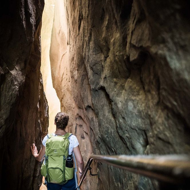 Wanderer mit Rucksack in der Wolfsschlucht umgeben von hohen Felswänden.