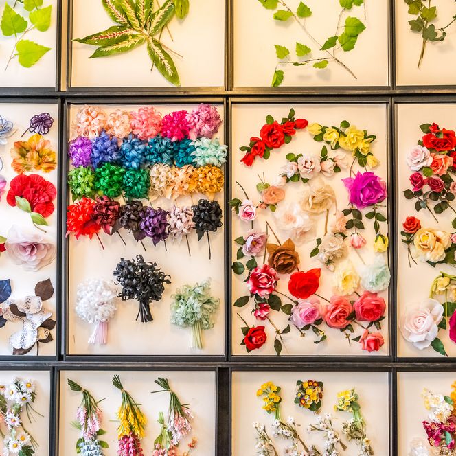 Bunte Seidenblumen und Blätter in einem gerahmten Arrangement.